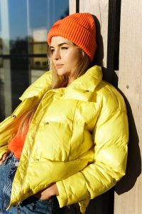 Stylish girl wearing yellow puffer and orange knitted hat